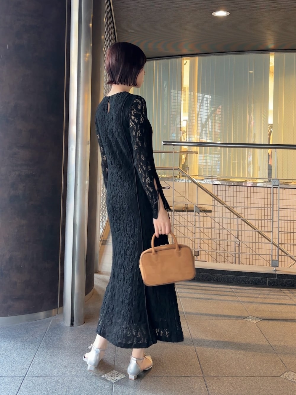 ブラック系のワンピース、イエロー系のハンドバッグ、シルバー系のパンプスを着用したレディースの冬コーディネートの4枚目の写真