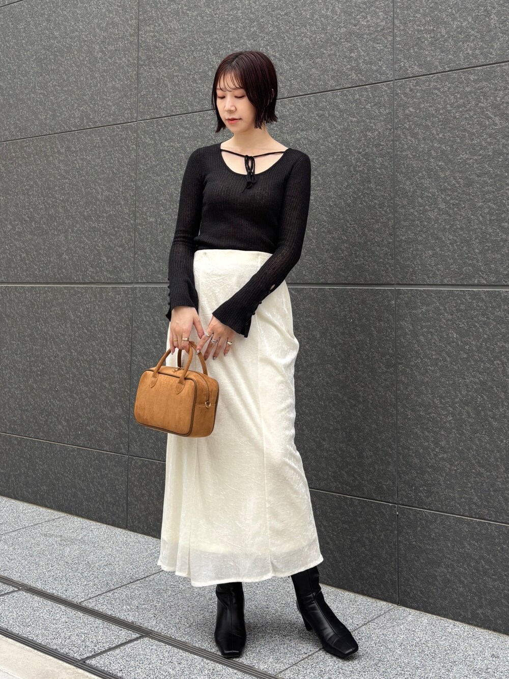 ホワイト系のスカート、イエロー系のハンドバッグ、ブラック系のブーツを着用したレディースの秋コーディネートの5枚目の写真