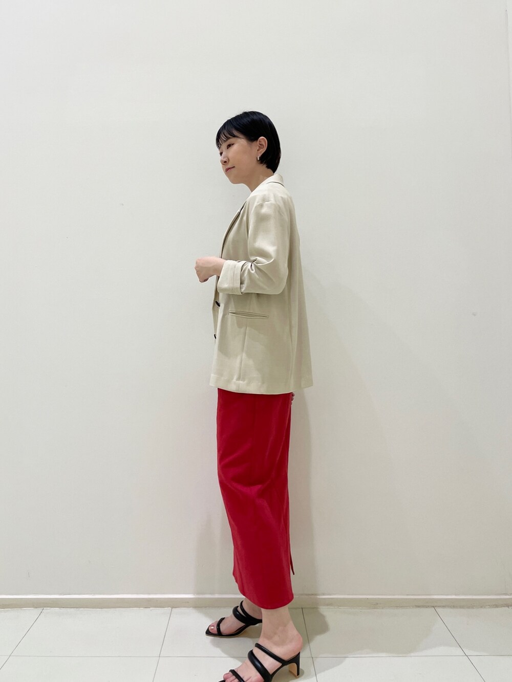 レッド系のスカート、ブラック系のサンダル、ベージュ系のテーラードジャケットを着用したレディースの春コーディネートの4枚目の写真