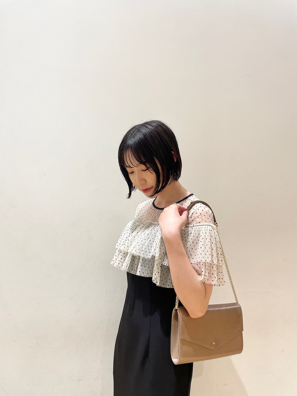 ゴールド系のハンドバッグ、ブラック系のドレス、ゴールド系のパンプスを着用したレディースの夏コーディネートの7枚目の写真