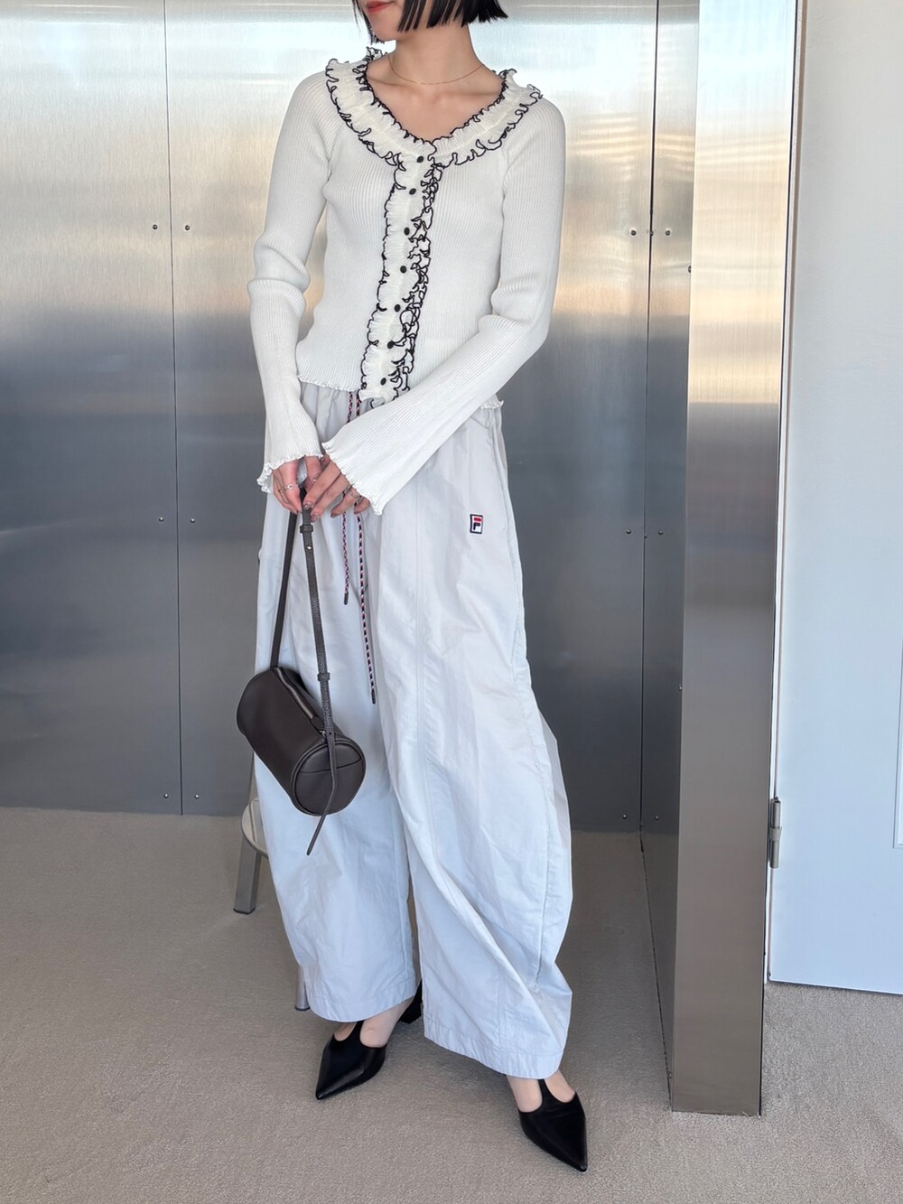 ベージュ系のその他パンツ、ホワイト系のニット/セーター、ブラック系のパンプスを着用したレディースの春コーディネートの2枚目の写真