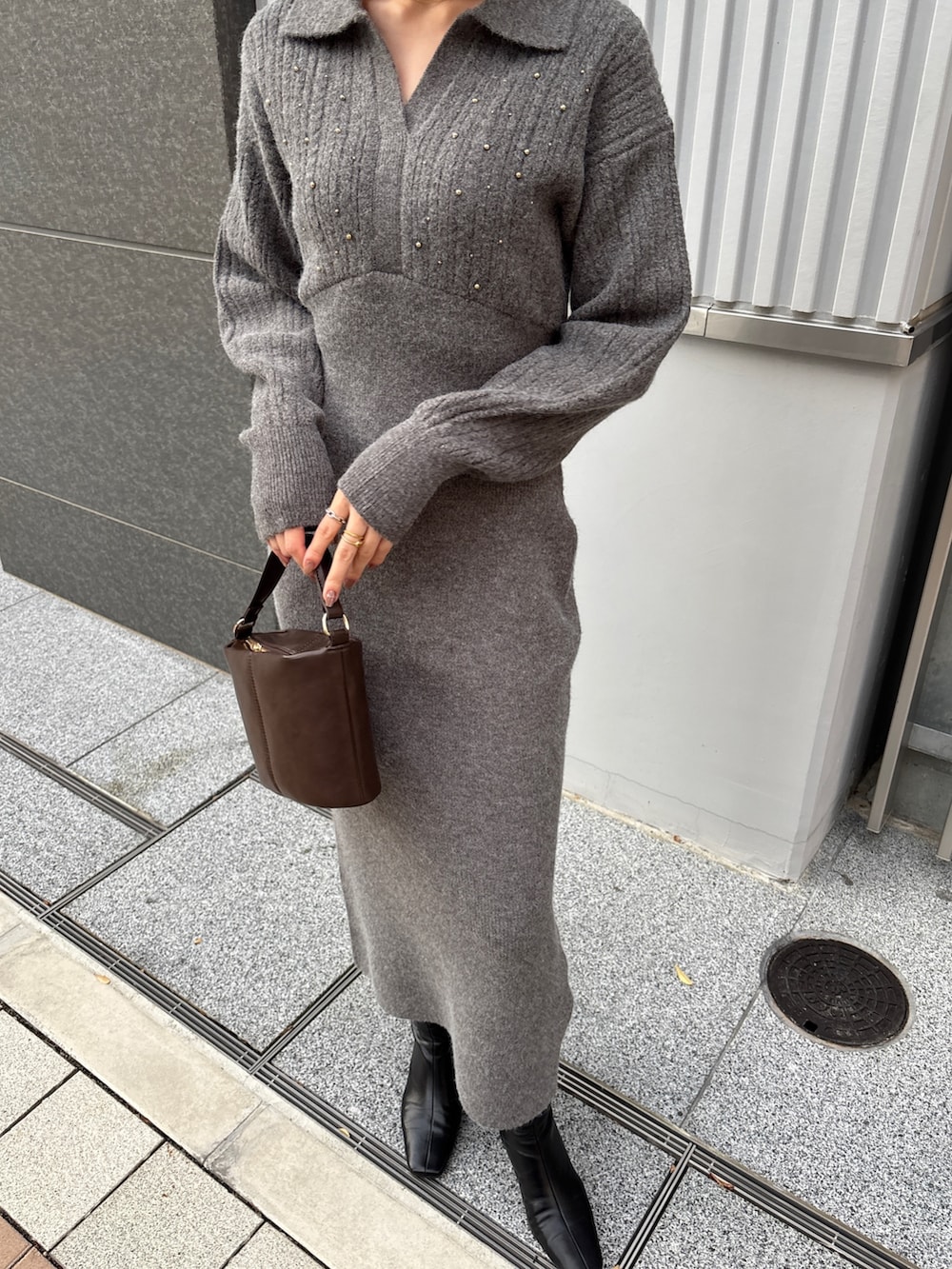 グレー系のワンピース、ブラウン系のハンドバッグ、ブラック系のブーツを着用したレディースの冬コーディネートの5枚目の写真