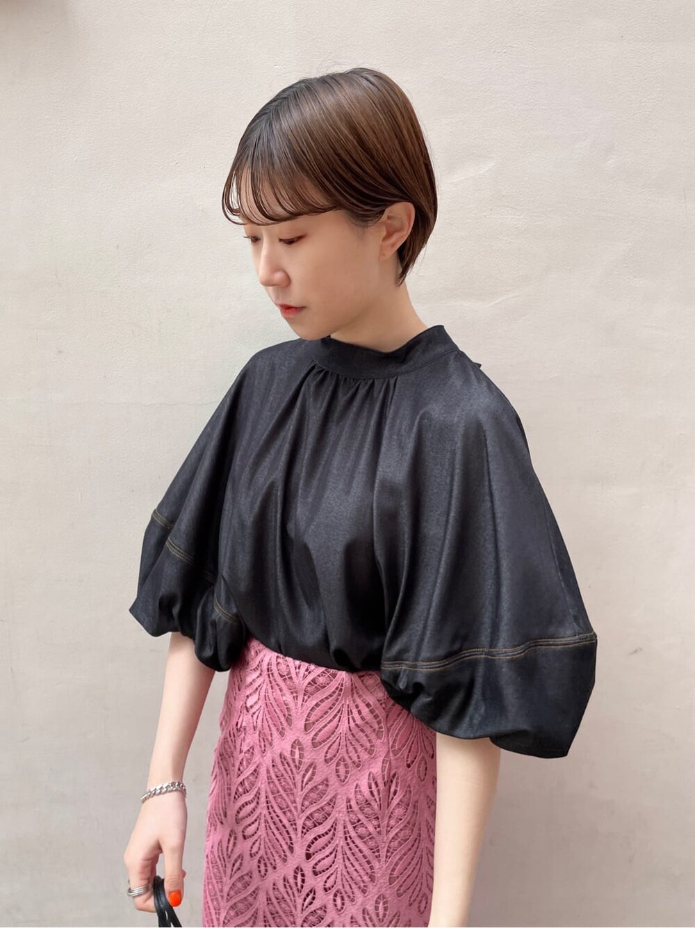 ブラック系のハンドバッグ、ブラック系のサンダル、ピンク系のスカートを着用したレディースの春コーディネートの7枚目の写真