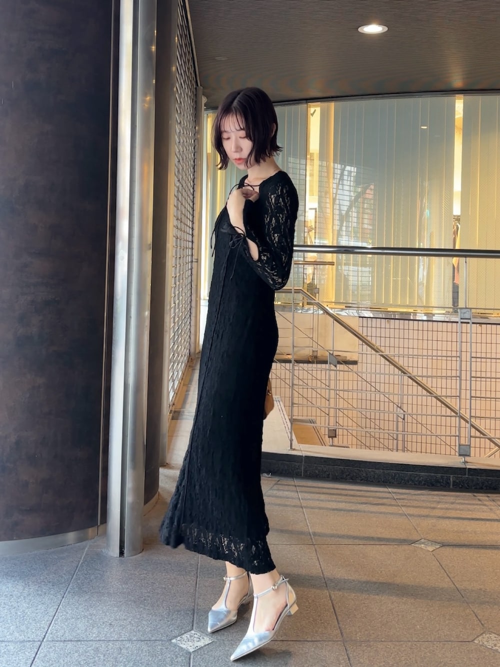 ブラック系のワンピース、イエロー系のハンドバッグ、シルバー系のパンプスを着用したレディースの冬コーディネートの3枚目の写真