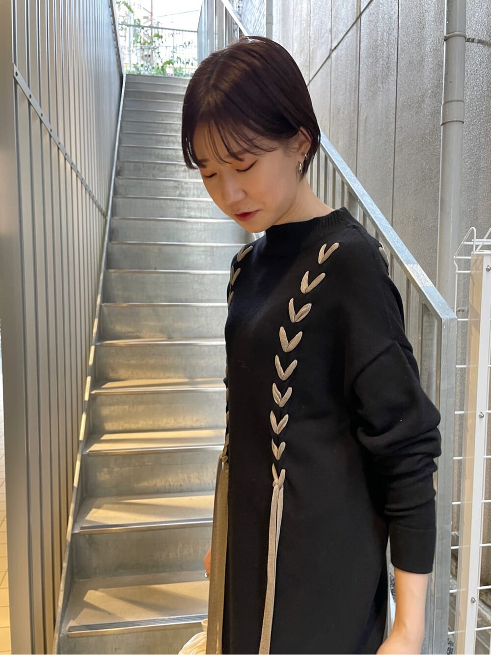 ブラック系のその他シューズ、ホワイト系のハンドバッグ、ブラック系のワンピースを着用したレディースの冬コーディネートの3枚目の写真