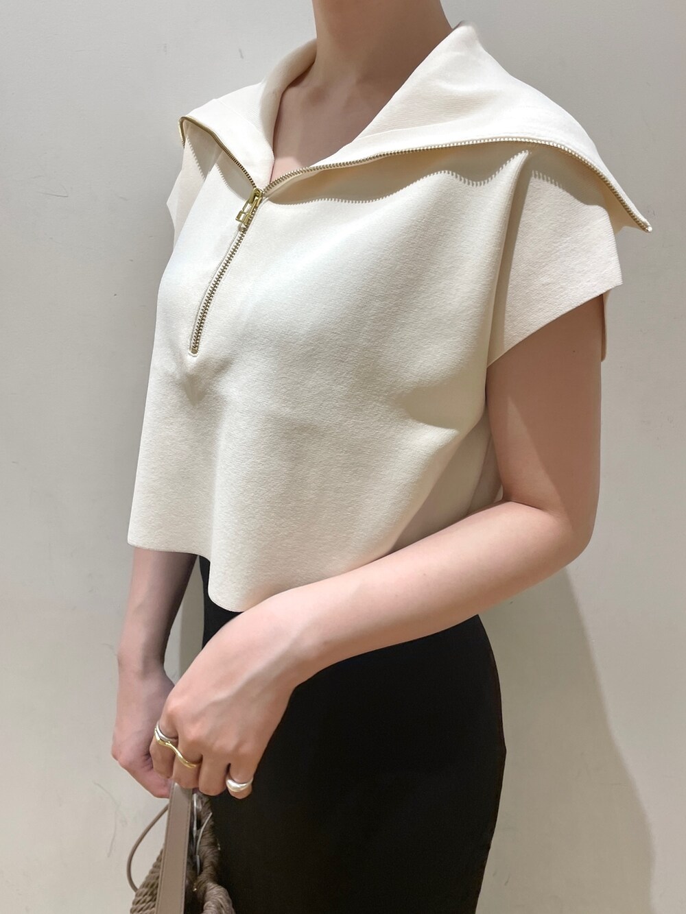 ブラック系のスカート、ホワイト系のニット/セーター、ブラウン系のハンドバッグを着用したレディースの春コーディネートの6枚目の写真