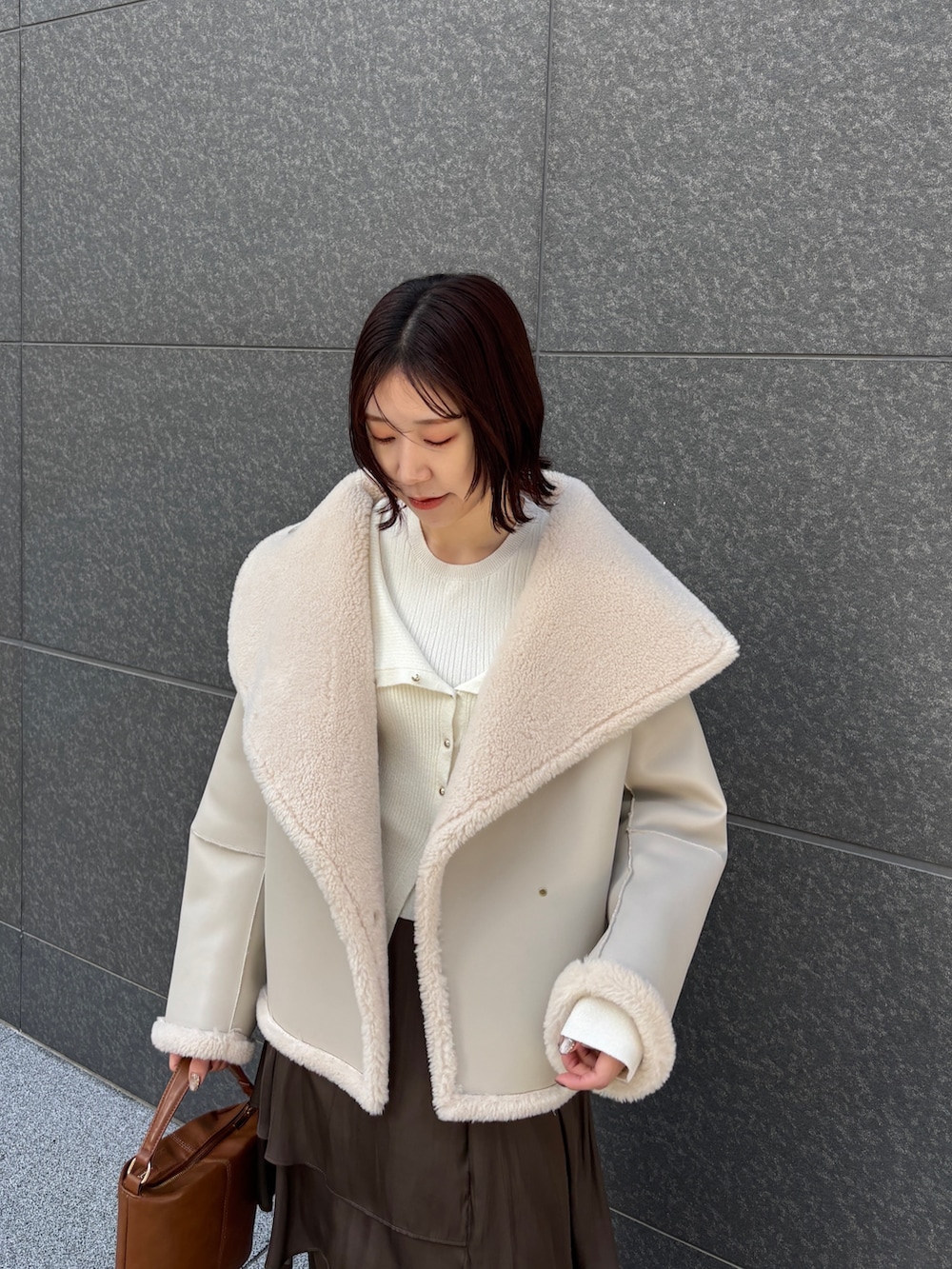 ホワイト系のムートンコート、ホワイト系のアンサンブル、イエロー系のハンドバッグを着用したレディースの冬コーディネートの5枚目の写真