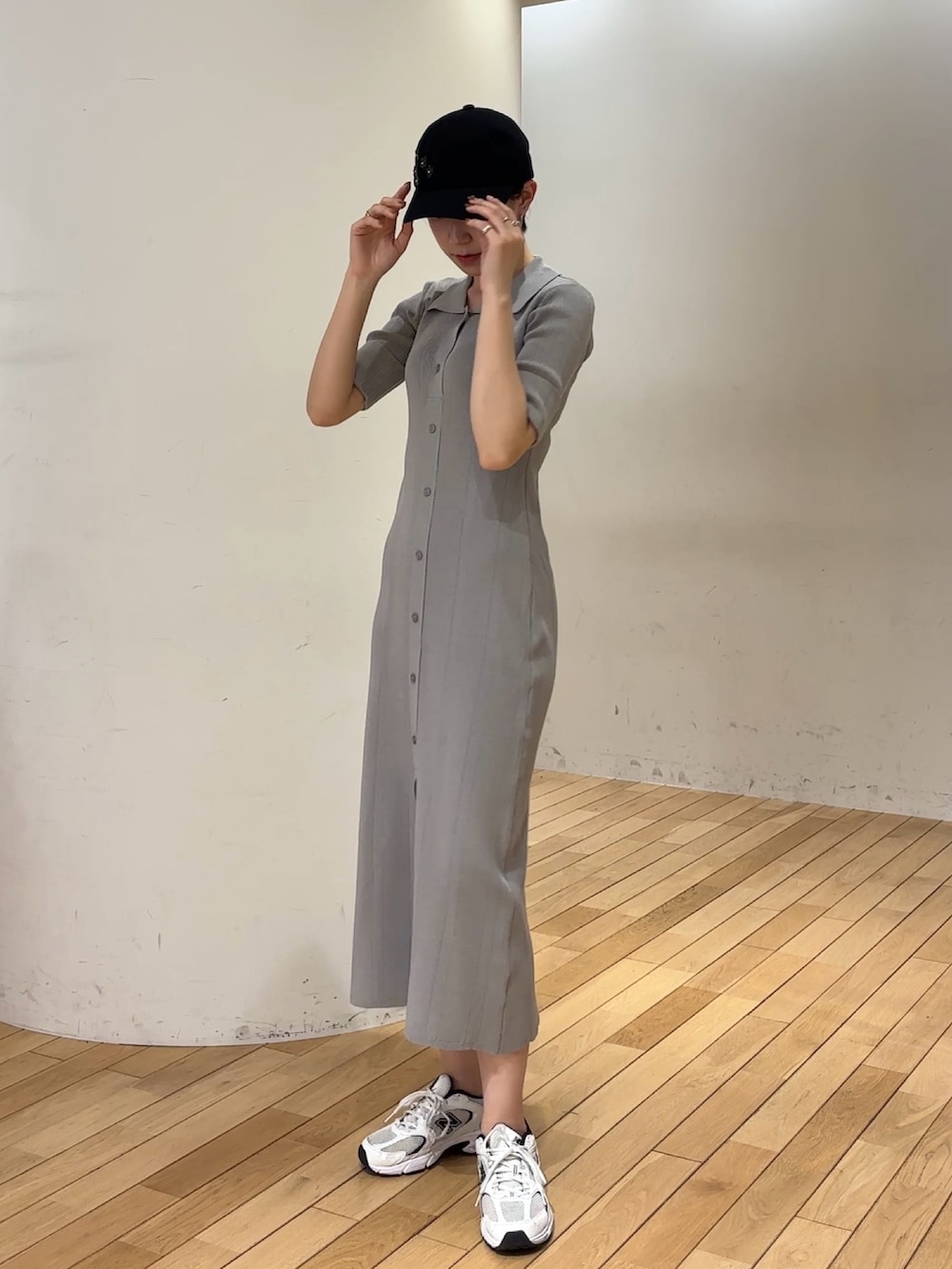 グレー系のワンピース、ブラック系のキャップを着用したレディースの春コーディネートの2枚目の写真