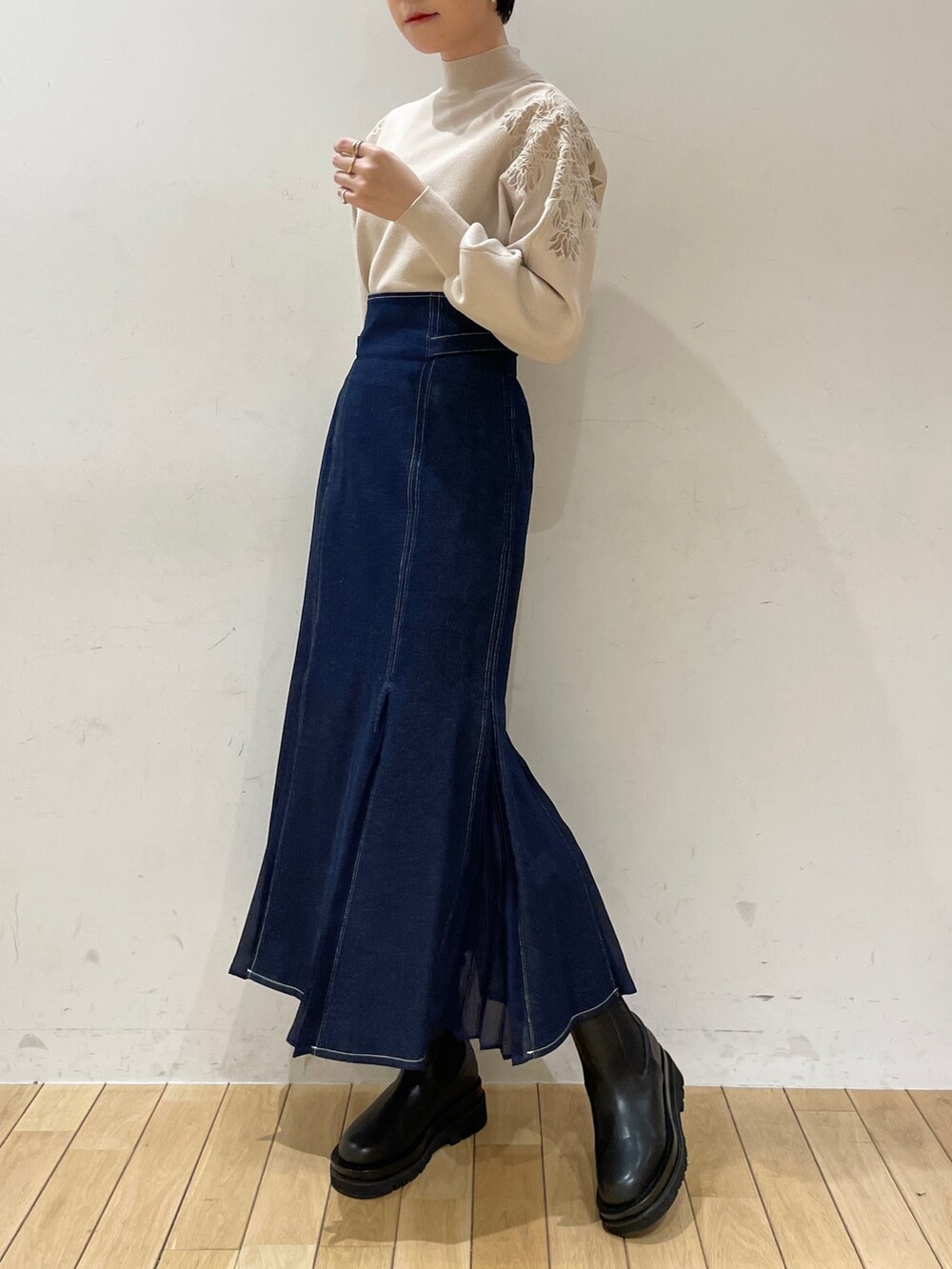 ホワイト系のニット/セーター、ブルー系のスカート、ブラック系のブーツを着用したレディースの冬コーディネートの5枚目の写真