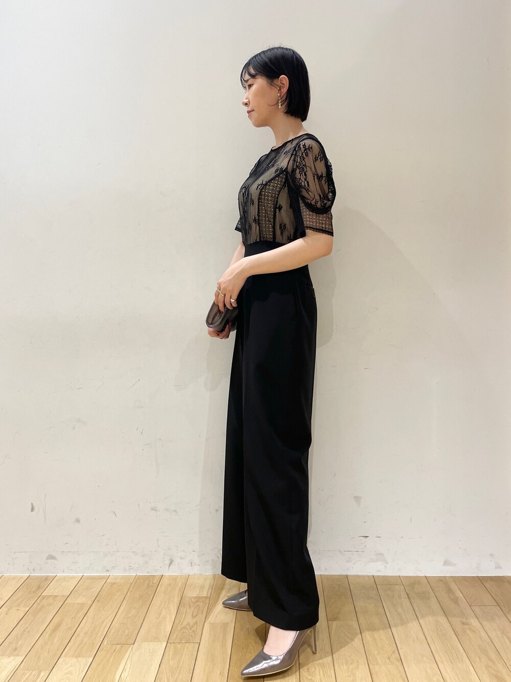 シルバー系のハンドバッグ、シルバー系のパンプス、ブラック系のパンツドレスを着用したレディースの夏コーディネートの4枚目の写真