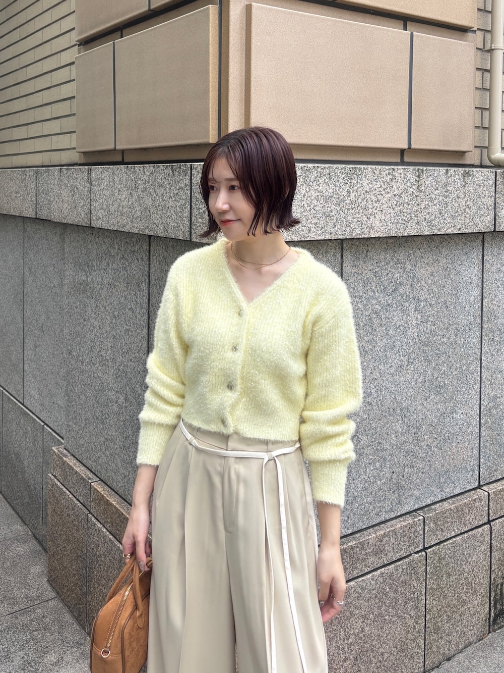 ベージュ系のその他パンツ、イエロー系のカーディガン/ボレロ、イエロー系のハンドバッグを着用したレディースの秋コーディネートの4枚目の写真