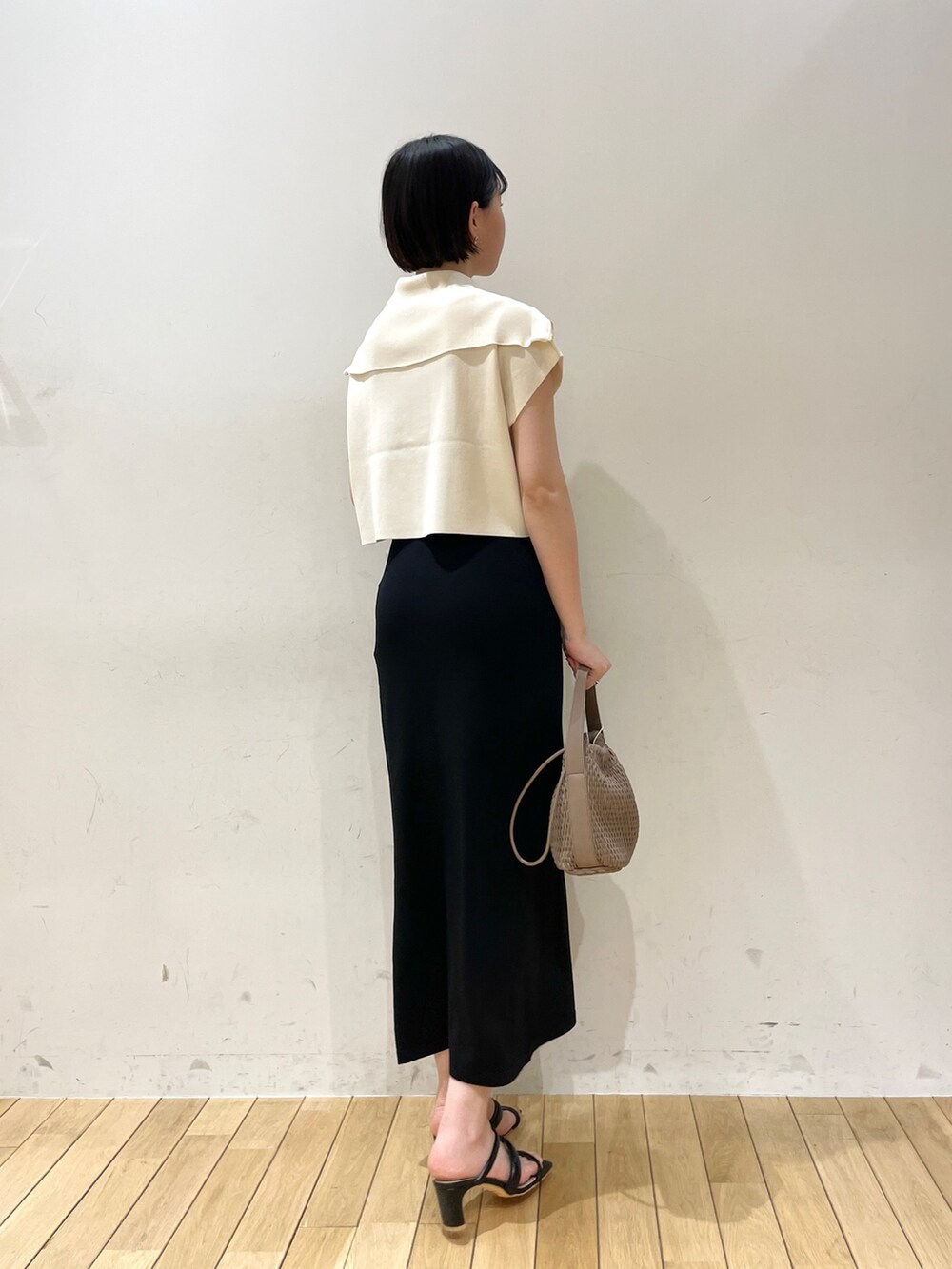 ブラック系のスカート、ホワイト系のニット/セーター、ブラウン系のハンドバッグを着用したレディースの春コーディネートの5枚目の写真