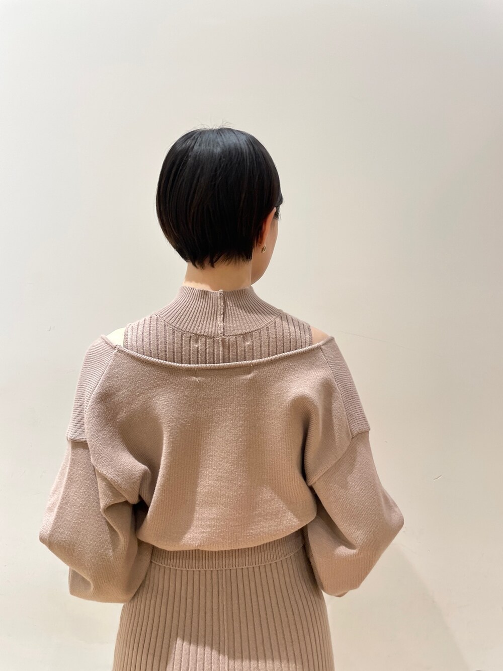 ベージュ系のワンピース、ホワイト系のハンドバッグ、ブラック系のブーツを着用したレディースの冬コーディネートの8枚目の写真