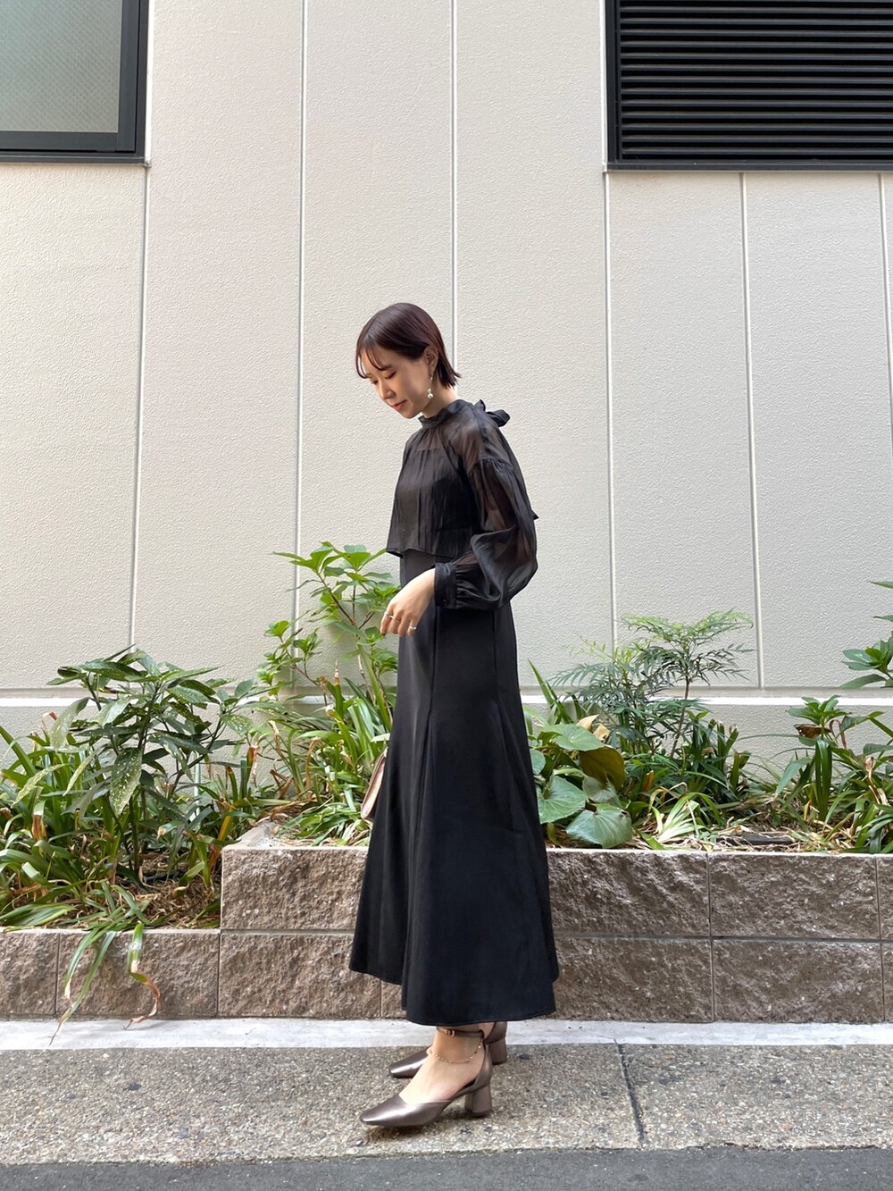 ブラック系のドレス、その他のパンプス、ゴールド系のハンドバッグを着用したレディースの秋コーディネートの3枚目の写真