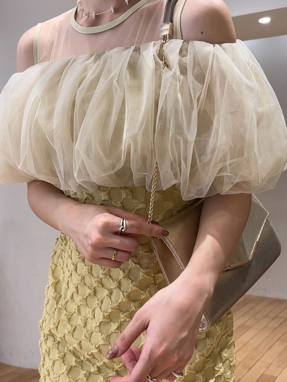 イエロー系のドレス、ゴールド系のパンプス、ゴールド系のクラッチバッグを着用したレディースの春コーディネートの5枚目の写真