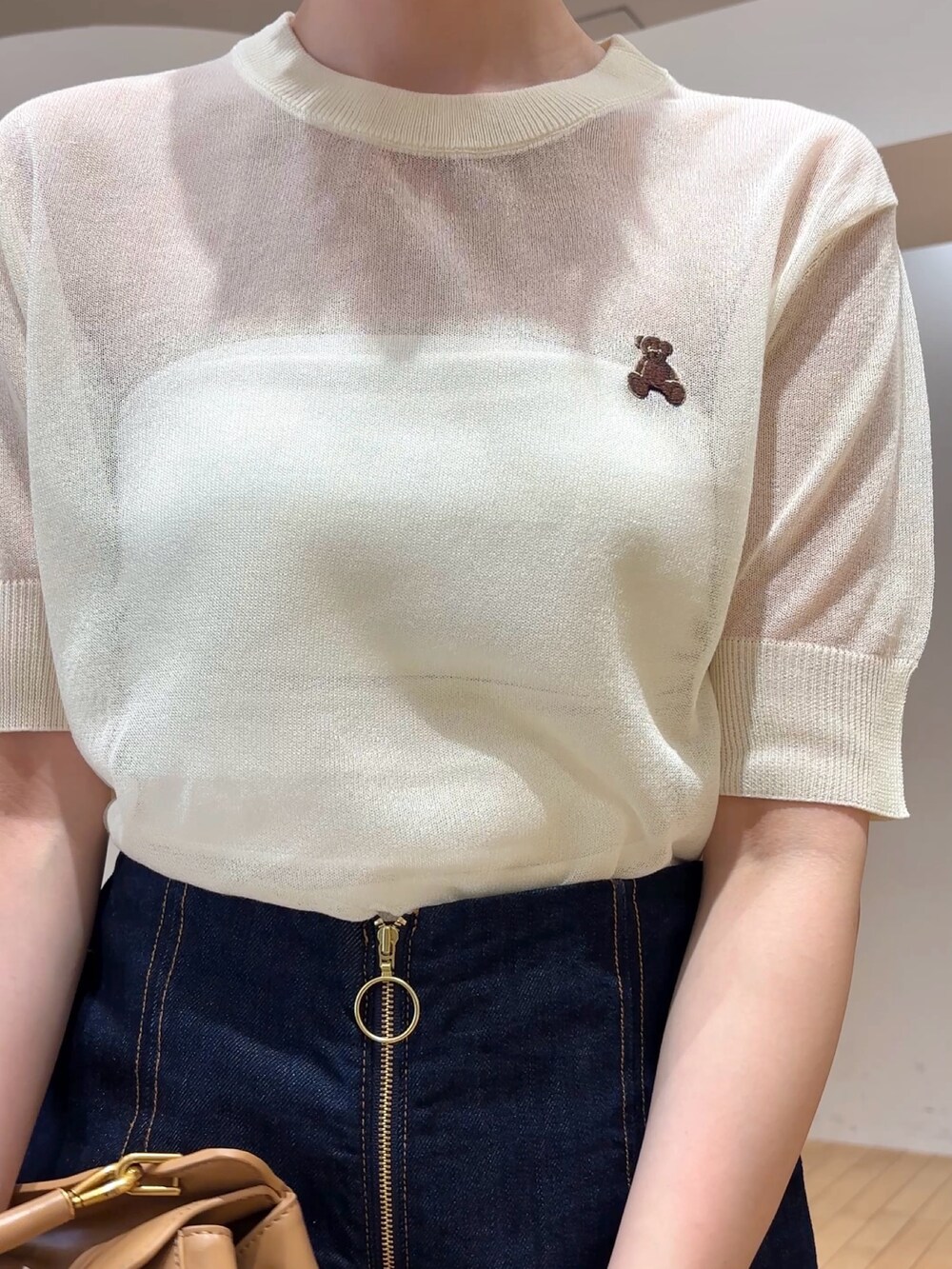 ブルー系のデニムパンツ、イエロー系のハンドバッグ、ブラック系のサンダルを着用したレディースの春コーディネートの4枚目の写真