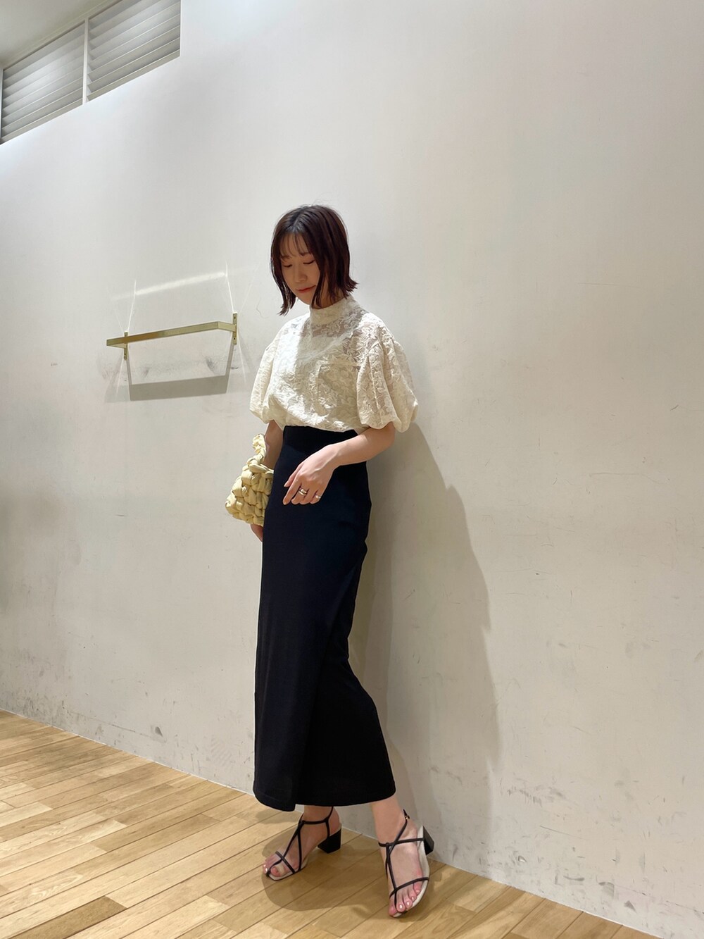 ベージュ系のハンドバッグ、ブラック系のサンダル、ホワイト系のシャツ/ブラウスを着用したレディースの夏コーディネートの2枚目の写真