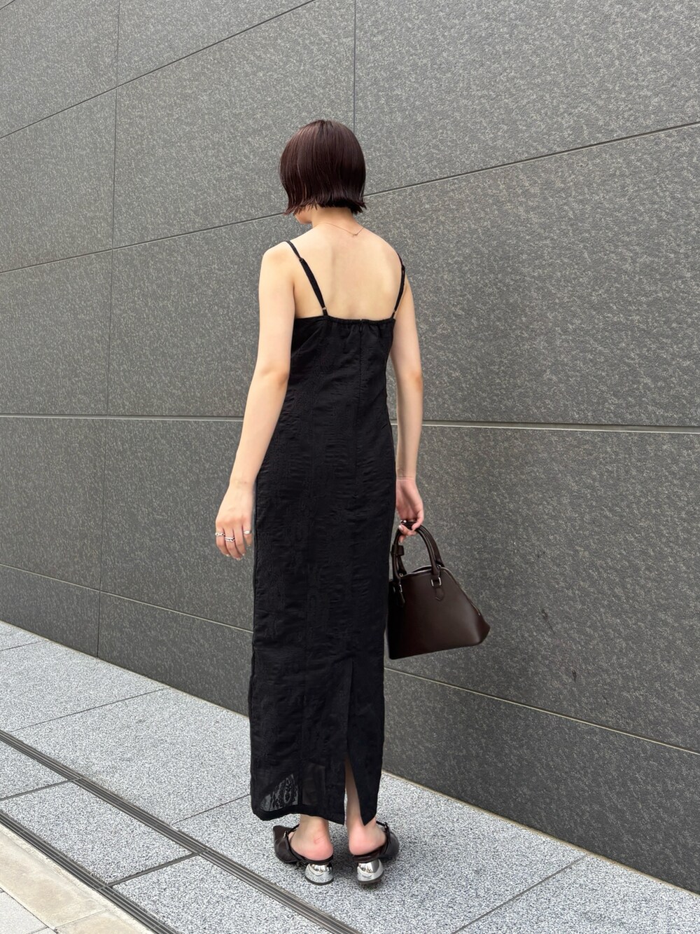 ブラック系のワンピース、ブラウン系のパンプス、ブラウン系のボストンバッグを着用したレディースの夏コーディネートの4枚目の写真
