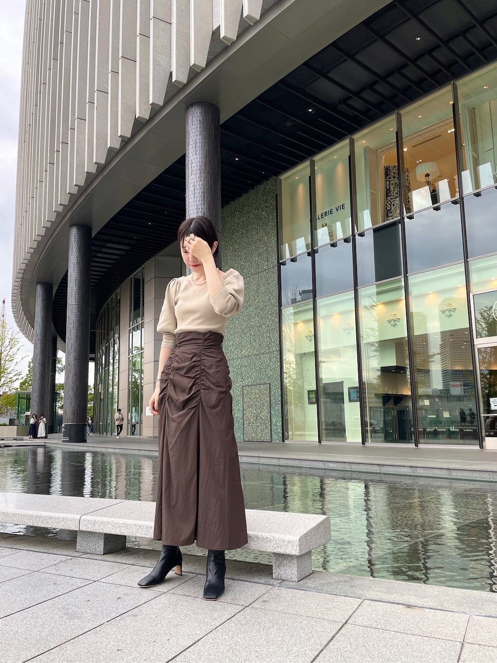 ブラック系のその他シューズ、ベージュ系のその他アウター、ブラウン系のスカートを着用したレディースの秋コーディネートの2枚目の写真