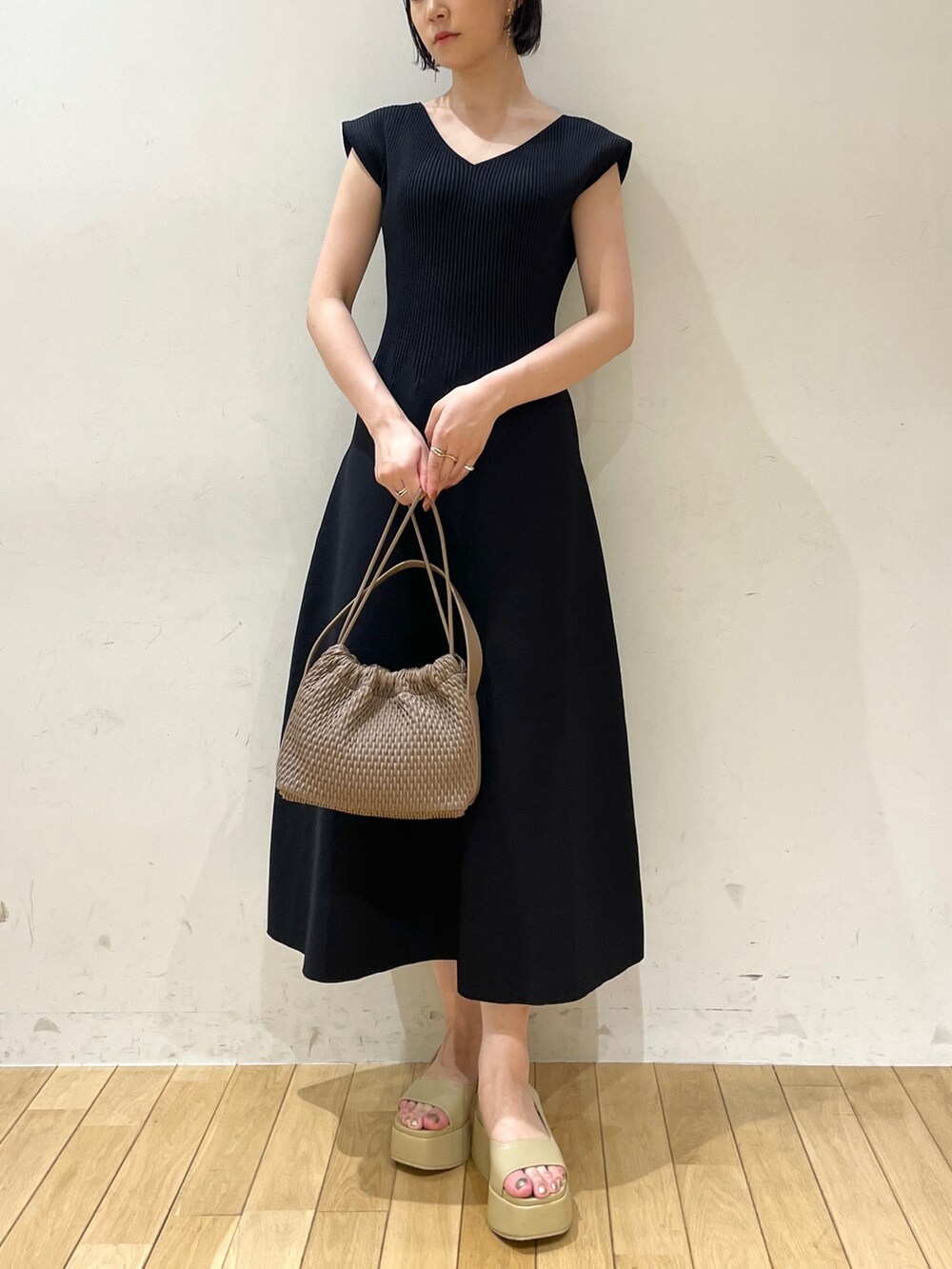 ブラック系のワンピース、ブラウン系のハンドバッグ、ベージュ系のサンダルを着用したレディースの夏コーディネートの6枚目の写真
