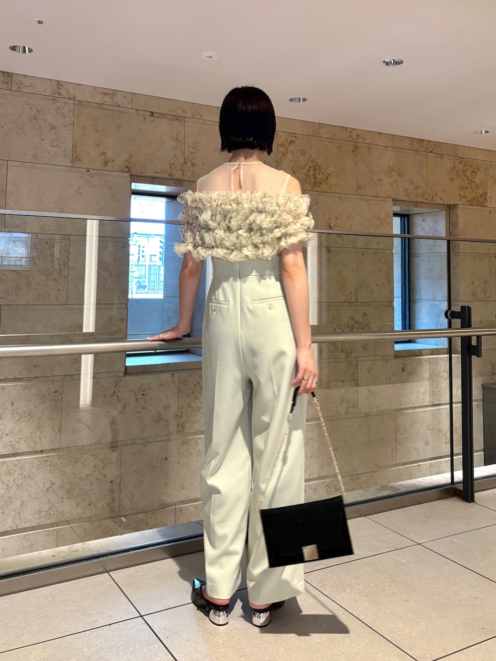 ブラック系のクラッチバッグ、ブラウン系のパンプス、グリーン系のパンツドレスを着用したレディースの秋コーディネートの4枚目の写真