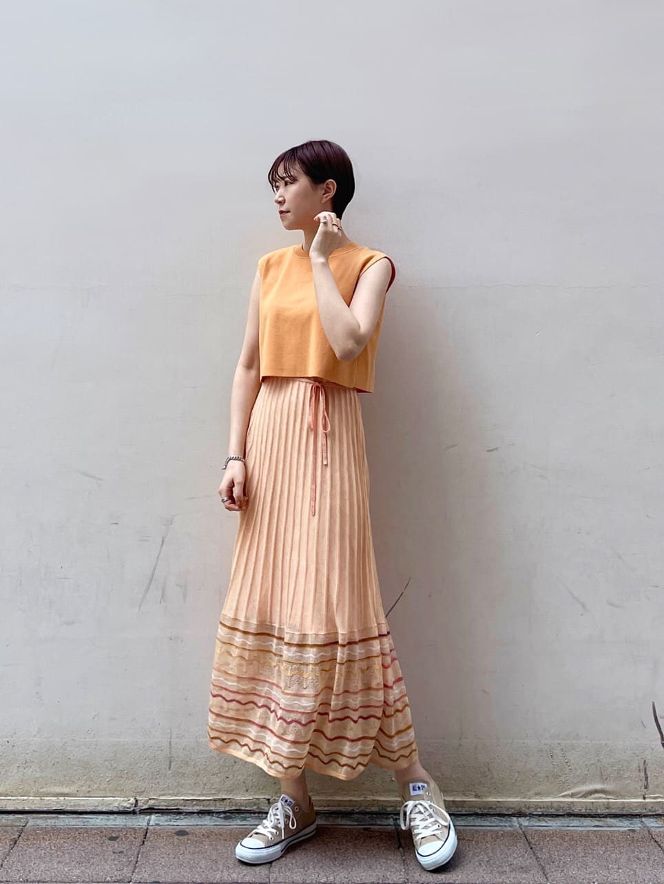 ホワイト系のテーラードジャケット、オレンジ系のワンピースを着用したレディースの春コーディネートの3枚目の写真