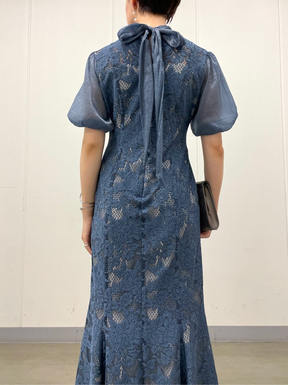 シルバー系のクラッチバッグ、ベージュ系のパンプス、ブルー系のドレスを着用したレディースの夏コーディネートの8枚目の写真