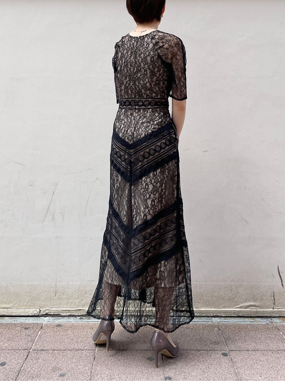 シルバー系のクラッチバッグ、ベージュ系のトレンチコート、シルバー系のパンプスを着用したレディースの冬コーディネートの4枚目の写真