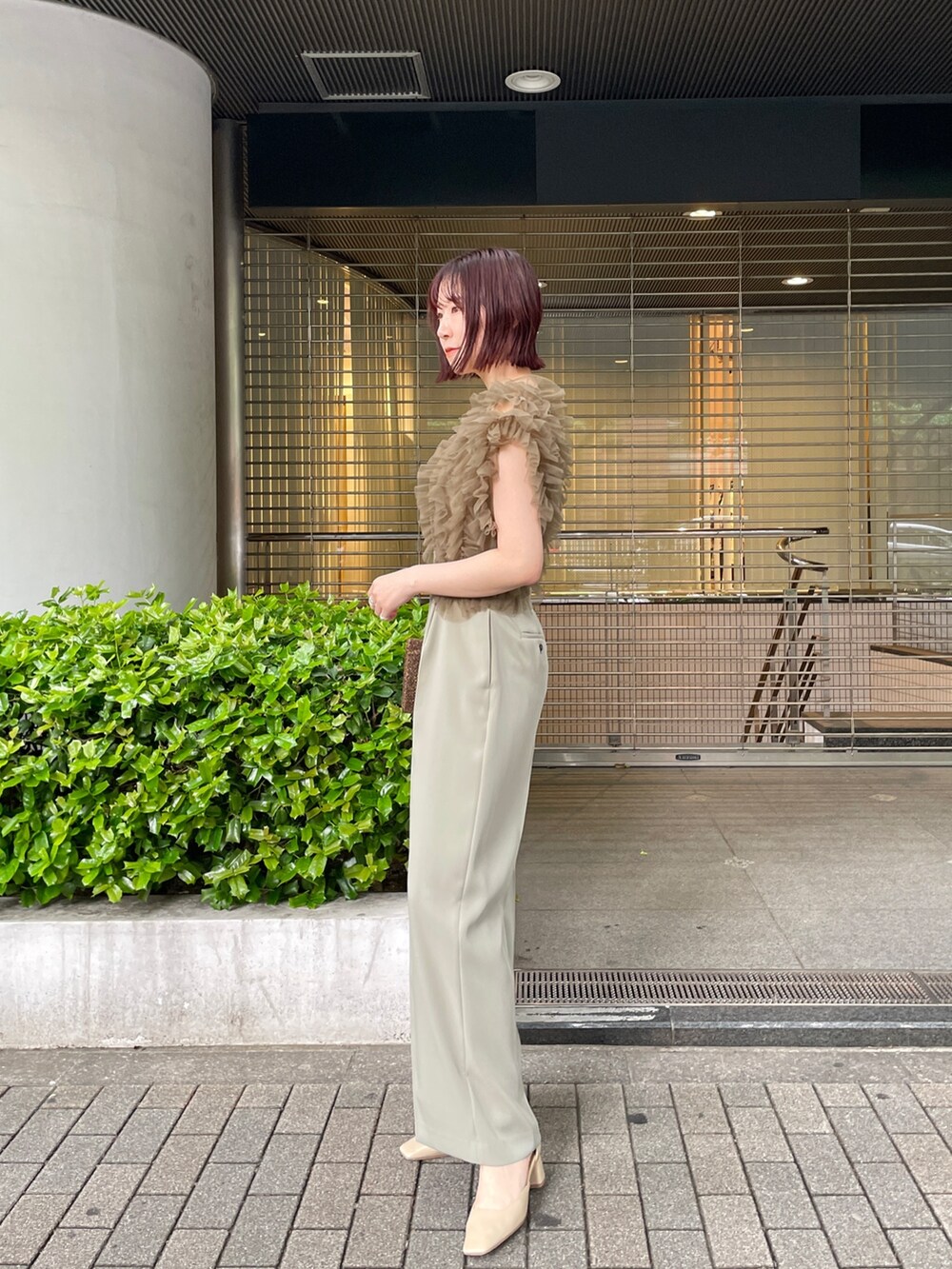 グリーン系のパンツドレス、ベージュ系のパンプスを着用したレディースの春コーディネートの4枚目の写真