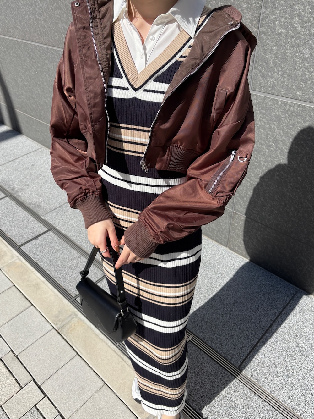 ベージュ系のワンピース、ブラック系のハンドバッグ、ブラウン系のブルゾンを着用したレディースの春コーディネートの6枚目の写真