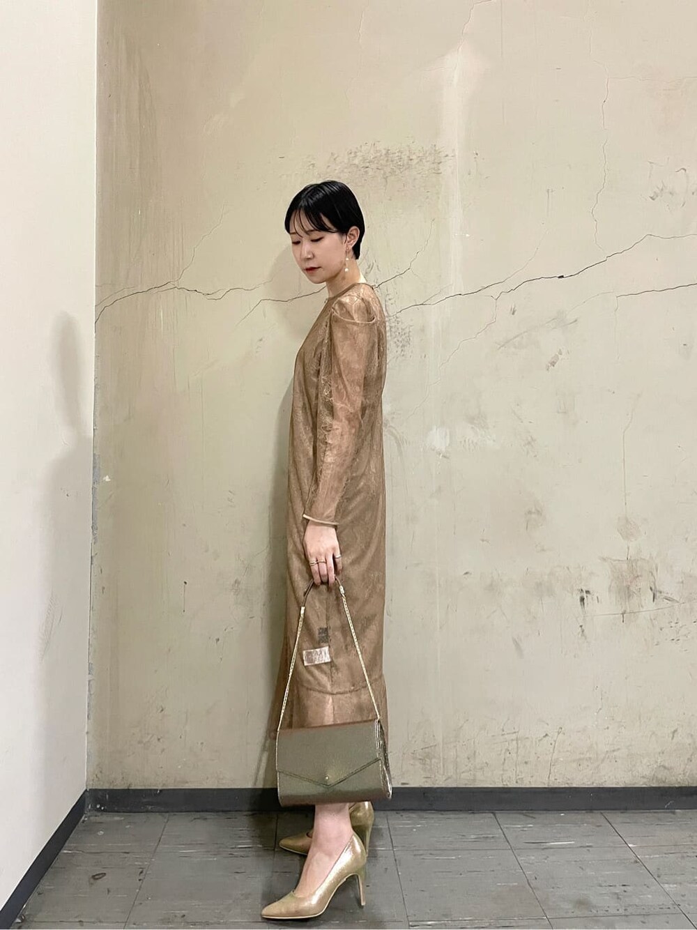 ゴールド系のパンプス、ベージュ系のドレス、ゴールド系のハンドバッグを着用したレディースの秋コーディネートの2枚目の写真