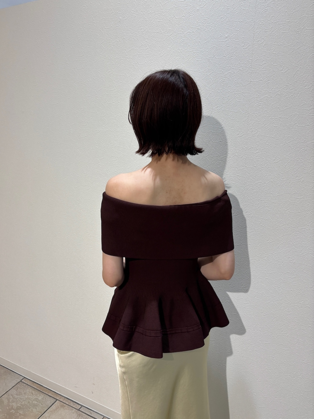 イエロー系のスカート、ブラウン系のハンドバッグ、ホワイト系のサンダルを着用したレディースの夏コーディネートの6枚目の写真