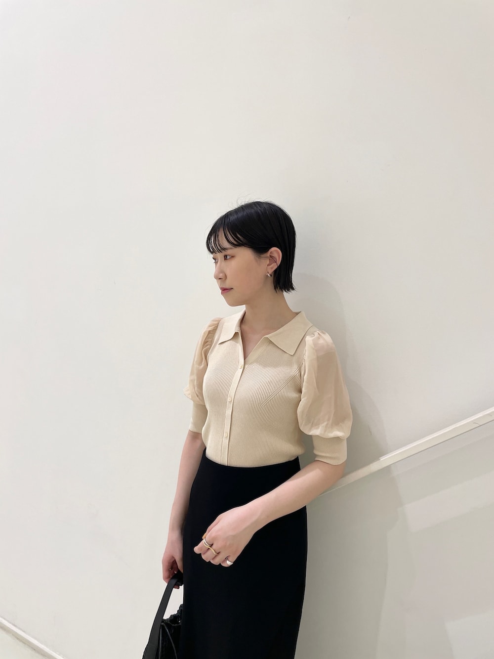 ブラック系のスカート、ホワイト系のニット/セーター、ブラック系のハンドバッグを着用したレディースの夏コーディネートの6枚目の写真