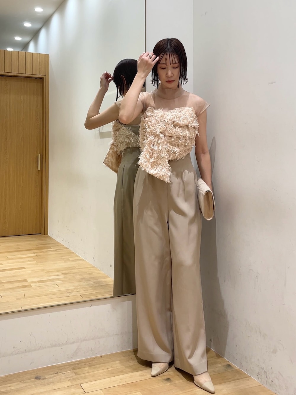 ベージュ系のパンプス、ベージュ系のパンツドレス、ベージュ系のクラッチバッグを着用したレディースの冬コーディネートの5枚目の写真