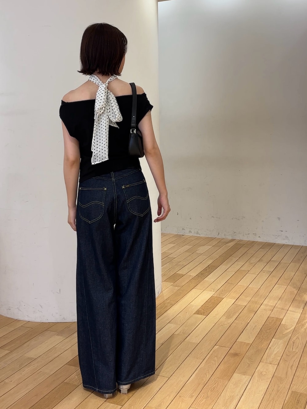 ブルー系のデニムパンツ、ブラック系のハンドバッグ、シルバー系のパンプスを着用したレディースの夏コーディネートの6枚目の写真