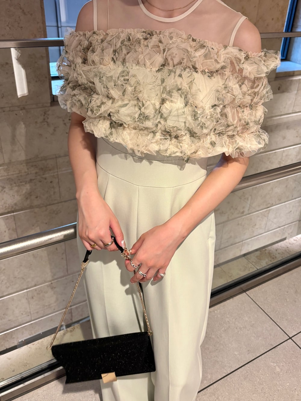 ブラック系のクラッチバッグ、ブラウン系のパンプス、グリーン系のパンツドレスを着用したレディースの秋コーディネートの6枚目の写真