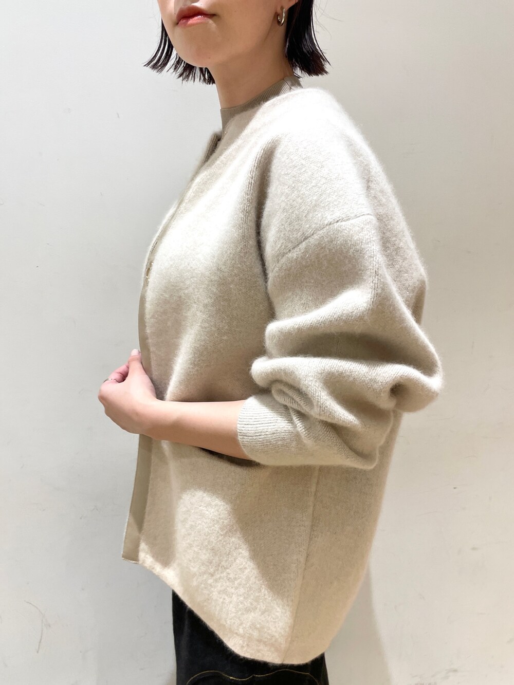 ブラック系のデニムスカート、ホワイト系のカーディガン/ボレロ、ベージュ系のニット/セーターを着用したレディースの秋コーディネートの8枚目の写真