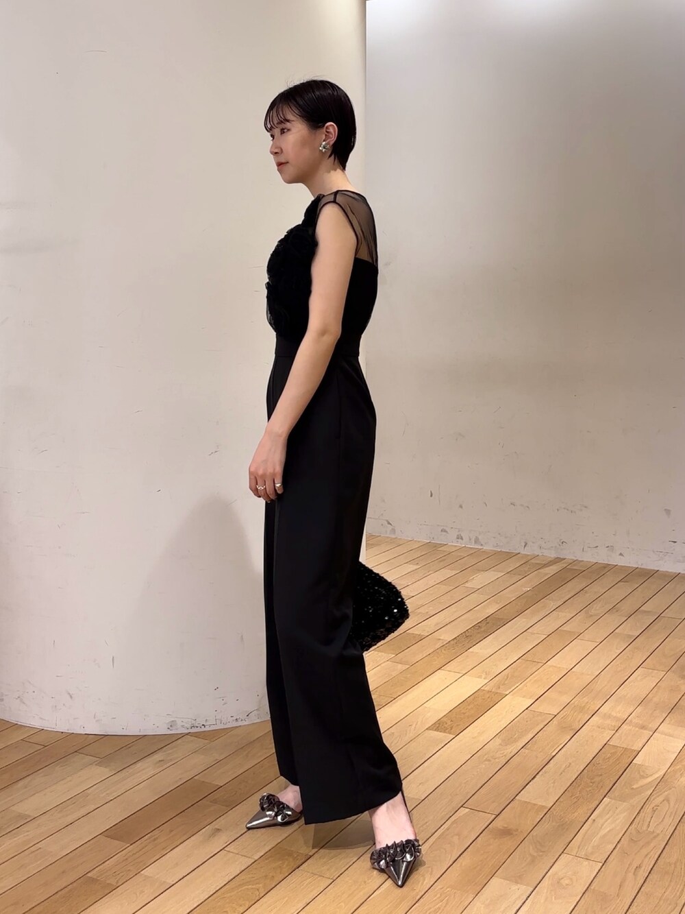 ブラック系のパンツドレス、ブラック系のショルダーバッグ、その他のパンプスを着用したレディースの春コーディネートの3枚目の写真