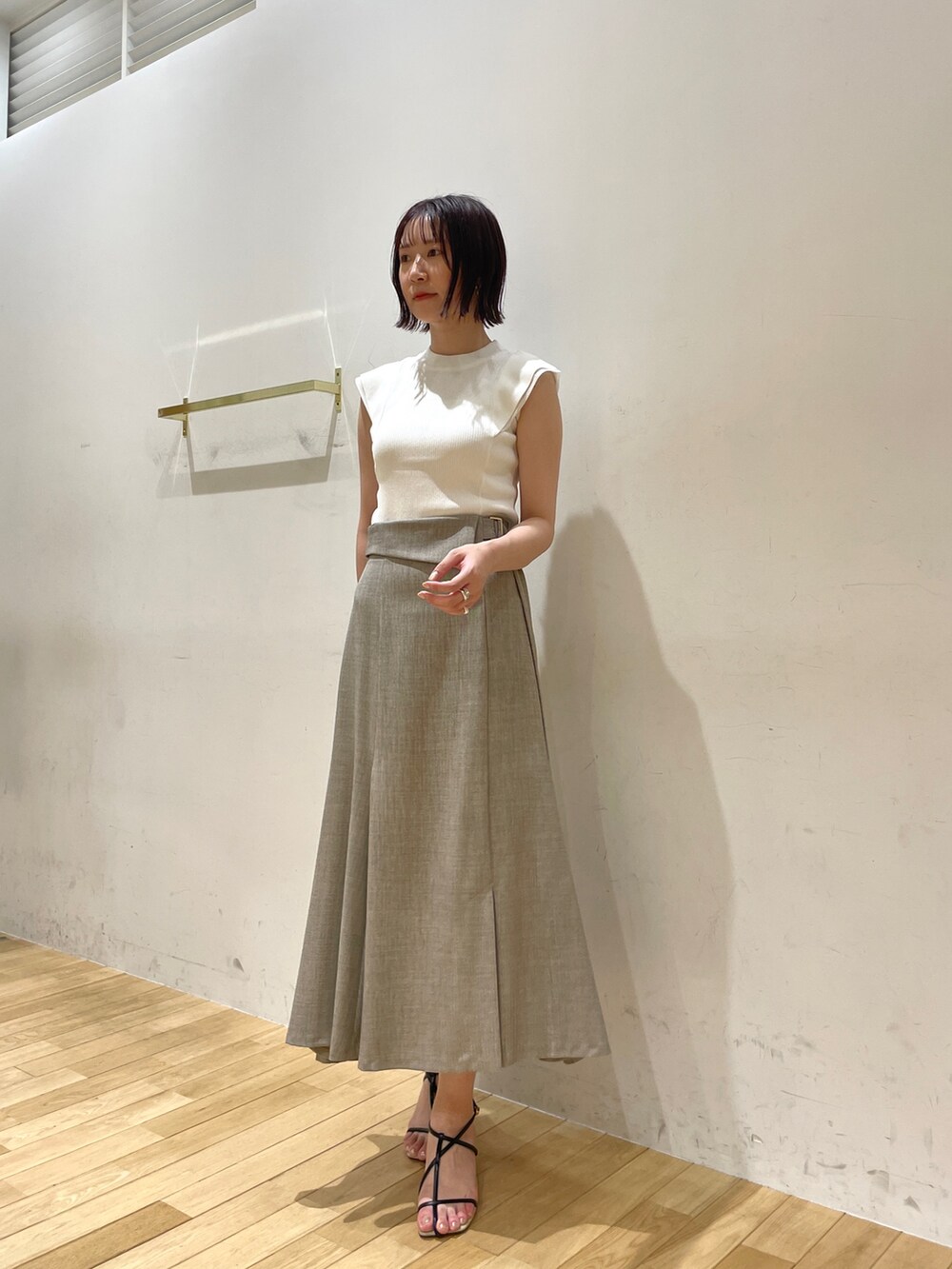 イエロー系のサンダル、ベージュ系のスカート、ホワイト系のニット/セーターを着用したレディースの夏コーディネートの2枚目の写真