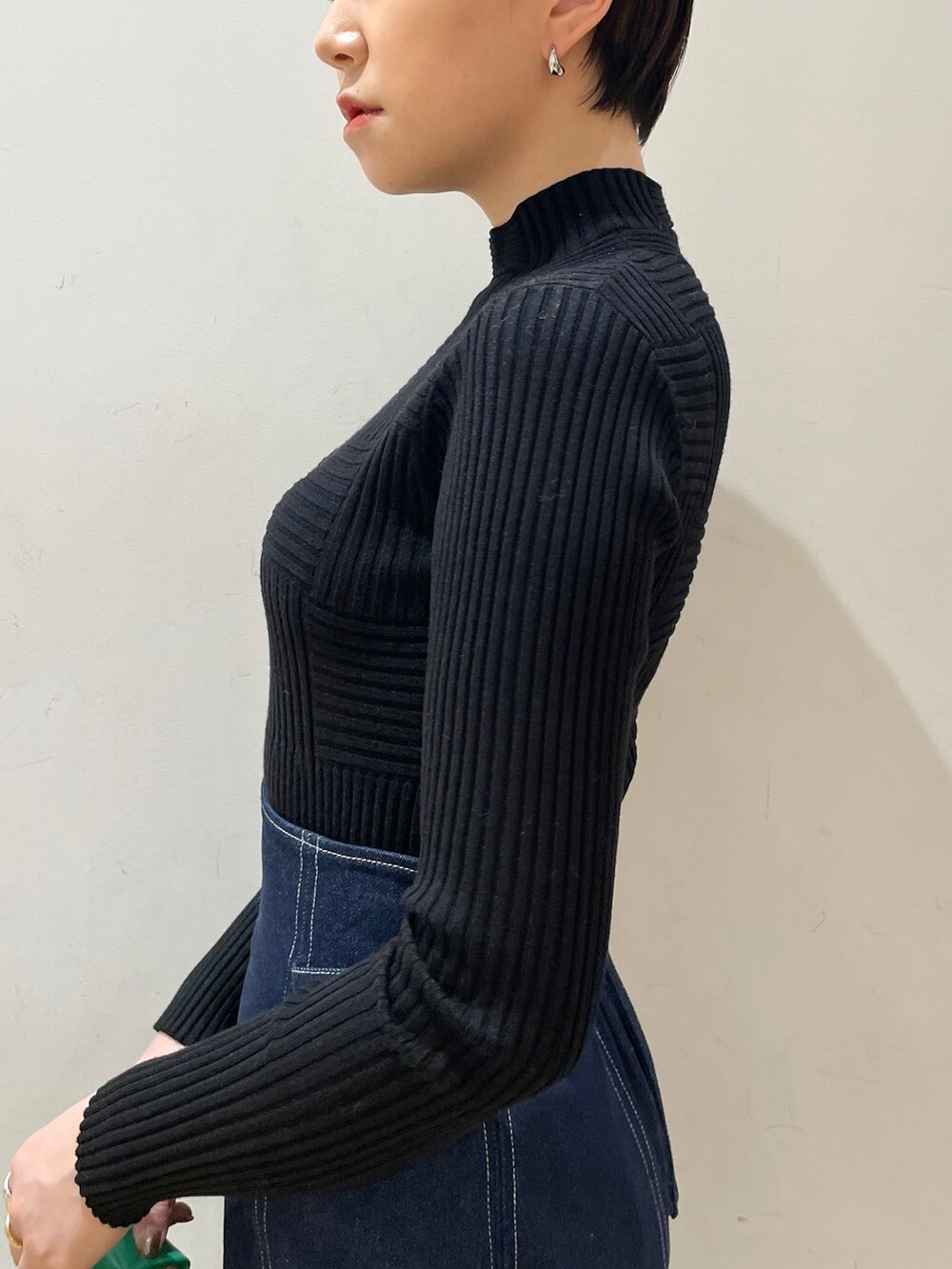 ブルー系のスカート、ブラック系のニット/セーター、グリーン系のハンドバッグを着用したレディースの冬コーディネートの8枚目の写真