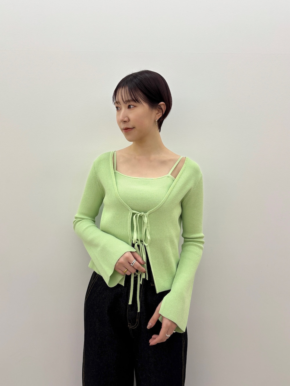 グリーン系のアンサンブル、ブラック系のデニムパンツ、ブラック系のサンダルを着用したレディースの春コーディネートの5枚目の写真