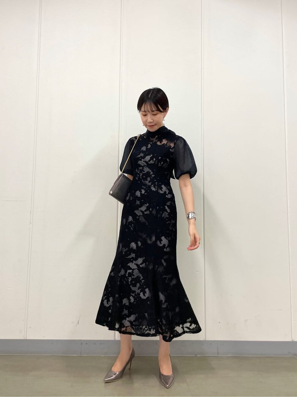 シルバー系のクラッチバッグ、シルバー系のパンプス、ブラック系のドレスを着用したレディースの夏コーディネートの3枚目の写真