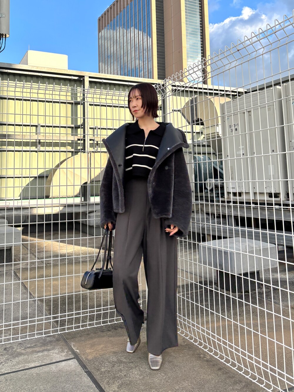 グレー系のその他パンツ、ブラック系のニット/セーター、グレー系のムートンコートを着用したレディースの冬コーディネートの5枚目の写真