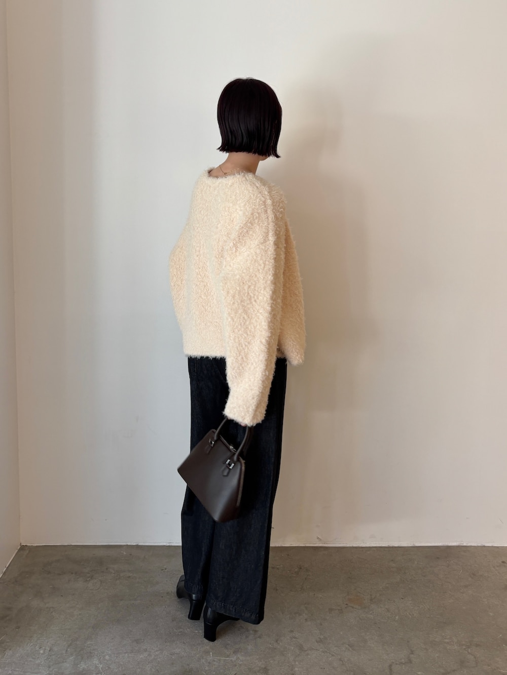 グレー系のアンサンブル、ホワイト系のカーディガン/ボレロ、ブラック系のデニムパンツを着用したレディースの秋コーディネートの2枚目の写真