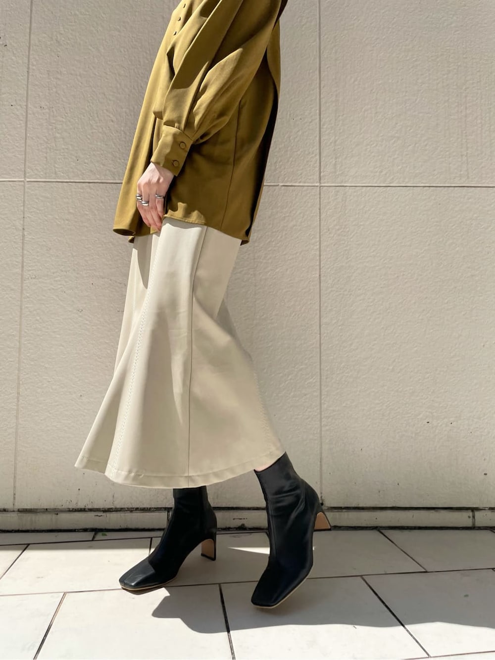 ホワイト系のスカート、ブラック系のその他シューズ、ベージュ系のその他アウターを着用したレディースの秋コーディネートの4枚目の写真