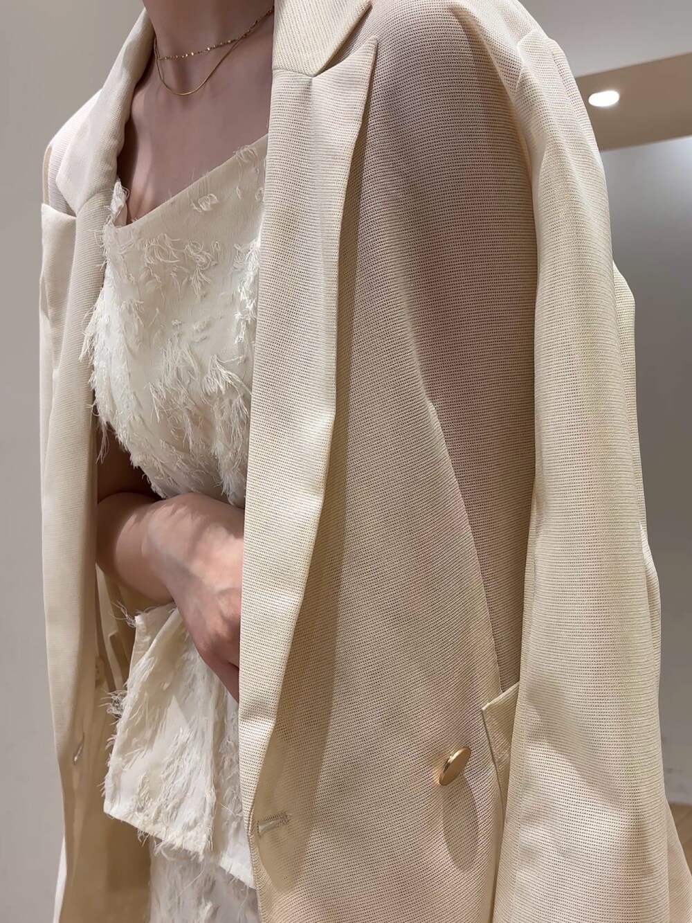 ホワイト系のスカート、ホワイト系のキャミソール、ホワイト系のテーラードジャケットを着用したレディースの夏コーディネートの6枚目の写真