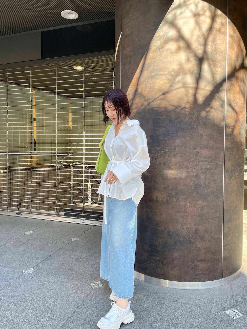 ホワイト系のシャツ/ブラウス、グリーン系のデニムスカート、ホワイト系のスニーカーを着用したレディースの春コーディネートの2枚目の写真