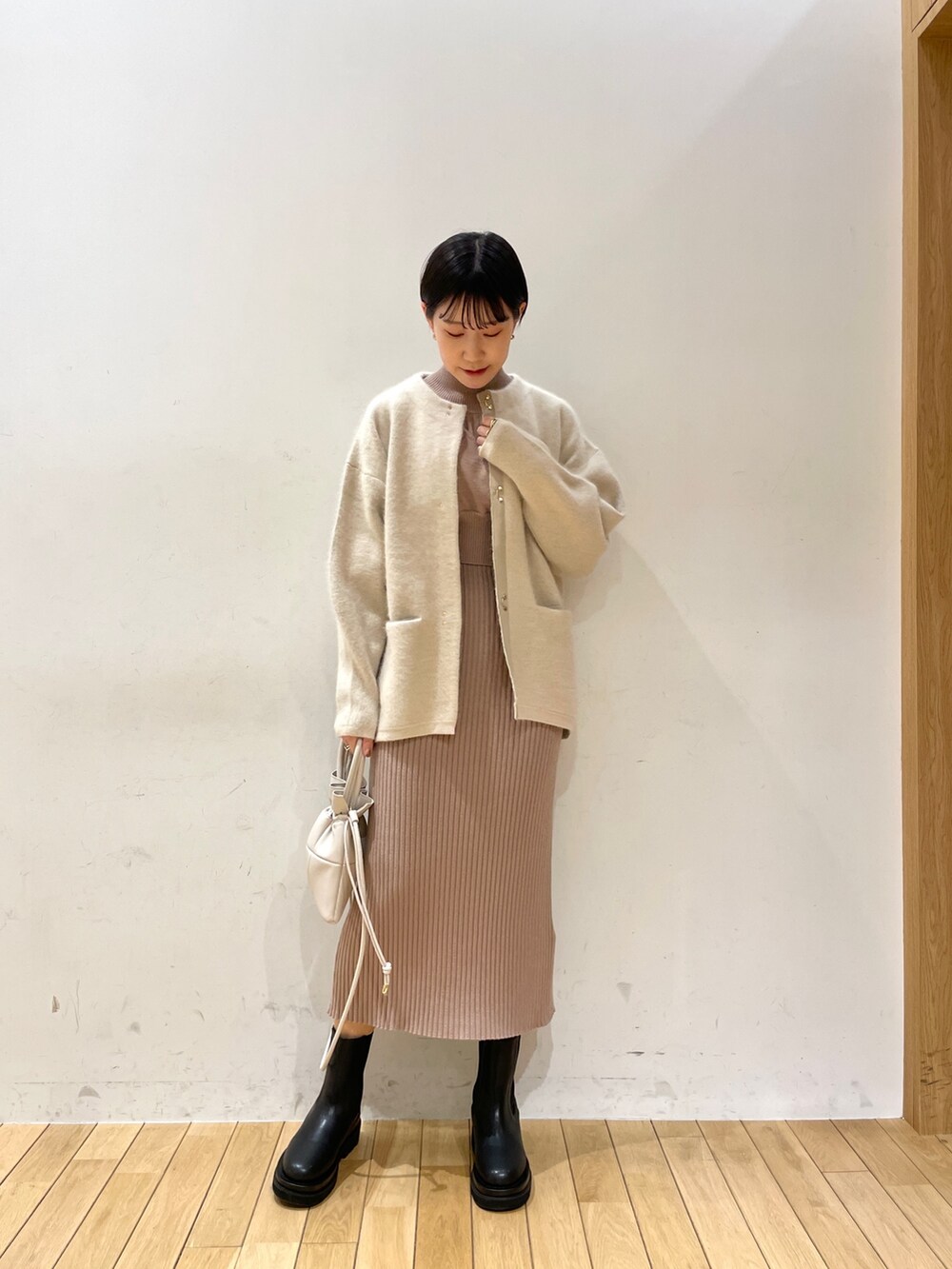 ホワイト系のカーディガン/ボレロ、ベージュ系のワンピース、ホワイト系のハンドバッグを着用したレディースの冬コーディネートの2枚目の写真