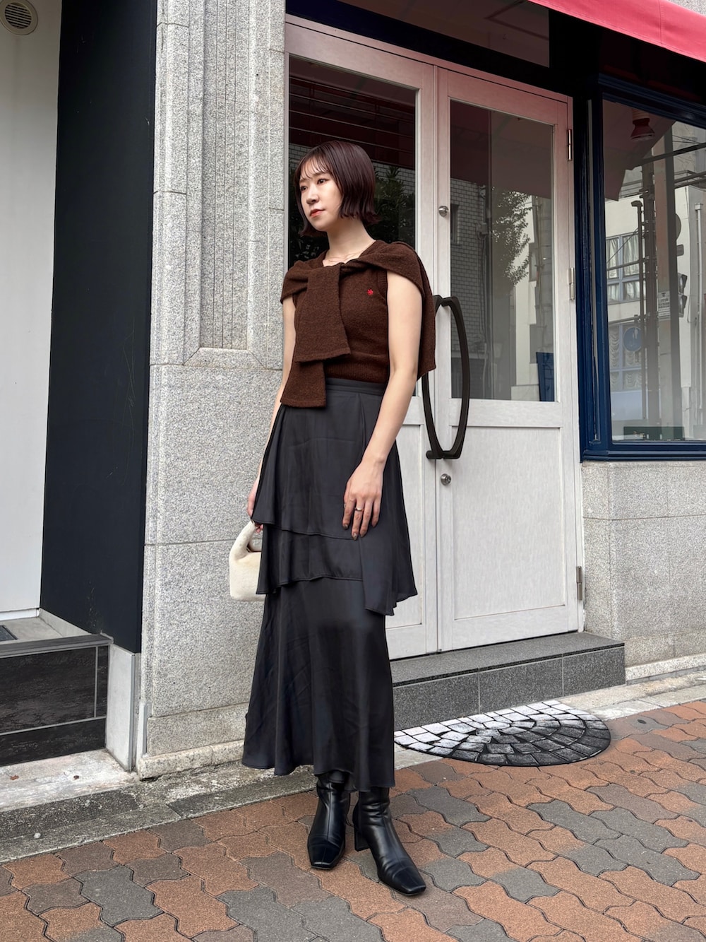 ブラック系のスカート、ブラウン系のアンサンブル、ブラック系のブーツを着用したレディースの秋コーディネートの6枚目の写真