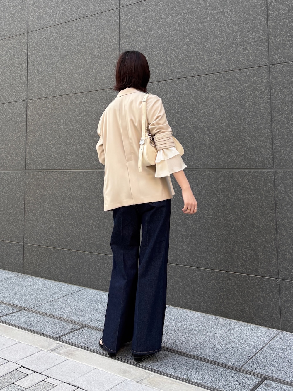 ホワイト系のシャツ/ブラウス、ホワイト系のハンドバッグ、ベージュ系のテーラードジャケットを着用したレディースの春コーディネートの2枚目の写真